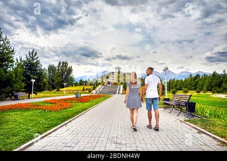 Happy couple in holding by hands and walking down the famous park in Almaty, Kazakhstan Stock Photo