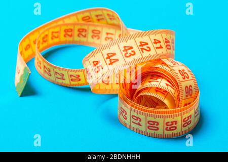 Perspective view of spiral measuring tape on blue background. Close up of slimming concept. Stock Photo