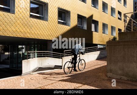 Boy on a bicycle makes a small climb in the midst of modern houses. Stock Photo