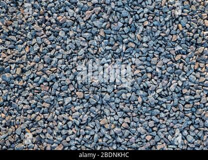 Crushed stone scattered on the ground. Large crushed stone for construction and repair work. Crushed stone obtained from granite rock. Background, tex Stock Photo
