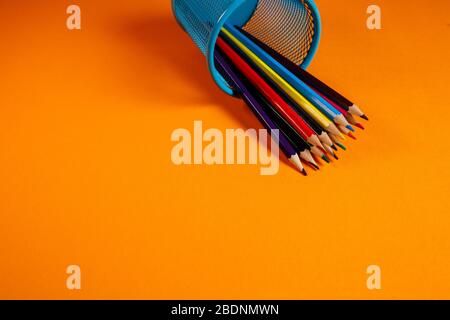 blue metal bucket with colored pencils for office on an orange background Stock Photo