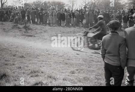 1960s, historical, spectators standing on a hilly ridge, watching a motorcycle scramble race, a sport which later became commonly known as motorcross racing. Stock Photo