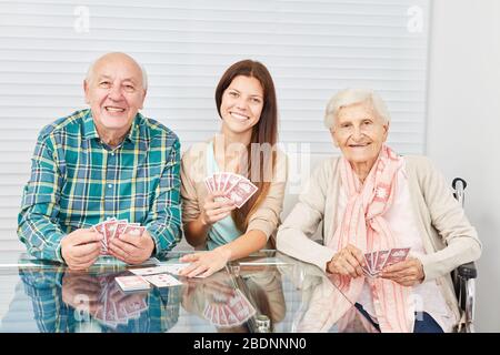 Happy couple of seniors playing cards with daughter or granddaughter Stock Photo