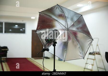 Photographic studio strobe lighting and reflective umbrella . Photo studio Silver Photo Studio Reflective Umbrella . Stock Photo