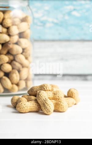 Tasty unpeeled peanuts. Peanuts in nutshell on white table. Stock Photo