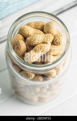 Tasty unpeeled peanuts. Peanuts in jar on white table. Stock Photo