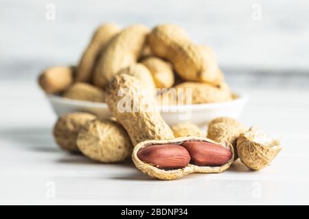 Tasty unpeeled peanuts. Peanuts in nutshell on white table. Stock Photo