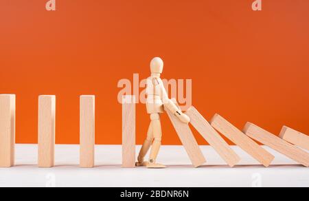 Wooden man stopping falling domino concept. Symbol of crisis, risk, management, leadership and determination. Domino effect. Fall of the crumbling bus Stock Photo