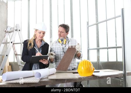 man and woman architect interior designer and foreman worker together with tiles samples and decorative materials discussing the project for interior Stock Photo