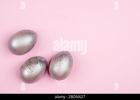Three easter silver eggs on pink background with copyspace