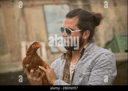 Farmer holds a chicken in his hand Stock Photo
