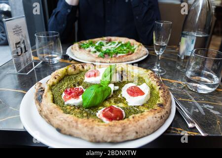 Delicious colorful pizza with pesto sauce, tomatoes, mozzarella di bufala campana & fresh basil. High quality close up with a blurry background. Stock Photo