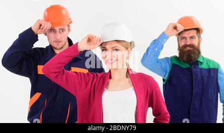 team work concept - two young men and woman in builders uniform and hard hats isolated on white background Stock Photo