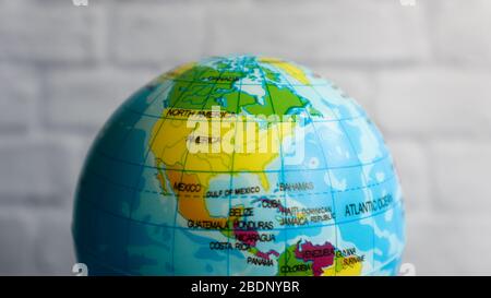 American cities on a part of the globe against the background of a white brick wall in the center of the frame. Small globe side of America Stock Photo