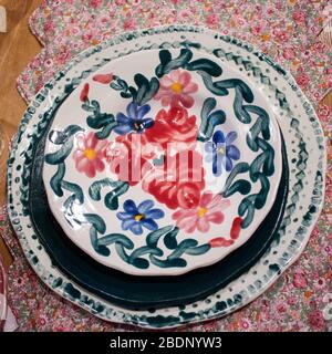 Porcelain white dish in red and blue flowers on red brocade on the table Stock Photo