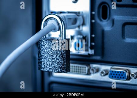 Closed lock hanging on a network cable plugged into a computer. The concept of security or blocking the Internet or the safety of personal data. Antiv Stock Photo