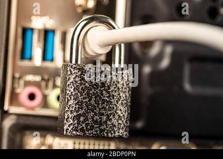 Closed lock hanging on a network cable plugged into a computer. The concept of security or blocking the Internet or the safety of personal data. Antiv Stock Photo