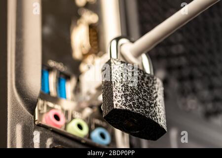 Closed lock hanging on a network cable plugged into a computer. The concept of security or blocking the Internet or the safety of personal data. Antiv Stock Photo