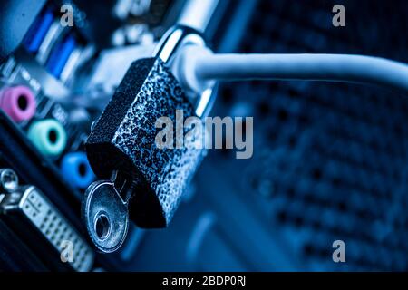 Closed lock hanging on a network cable plugged into a computer. The concept of security or blocking the Internet or the safety of personal data. Antiv Stock Photo