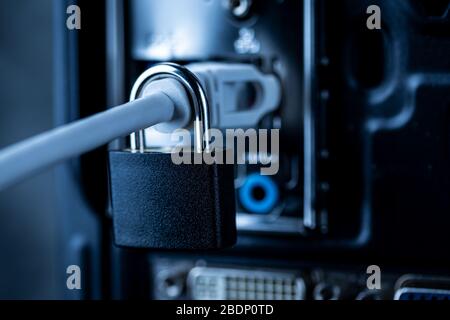 Closed lock hanging on a network cable plugged into a computer. The concept of security or blocking the Internet or the safety of personal data. Antiv Stock Photo