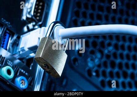 Closed lock hanging on a network cable plugged into a computer. The concept of security or blocking the Internet or the safety of personal data. Antiv Stock Photo
