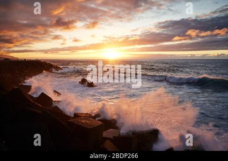 Scenic sunset with waves crashing on rocks, Puerto de la Cruz, Tenerife, Spain. Stock Photo