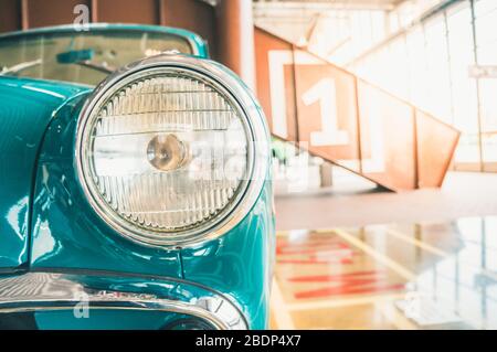 Details of blue retro vintage car with round headlamp standing indoors Stock Photo