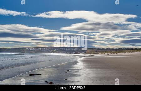 CULLEN BAY BEACH AND TOWN MORAY SCOTLAND EARLY MORNING WALKERS ON THE SANDY BEACH Stock Photo