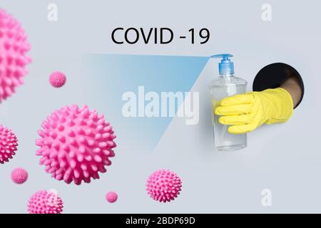 Woman in yellow gloves disinfects virus with special gel in bottle to protect against Coronavirus infection. Text - COVID-19. Stock Photo
