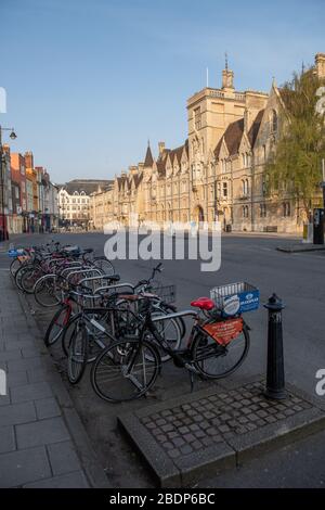 Bikes stand silently in a deserted Broad Street, Oxford.  Balliol College behind