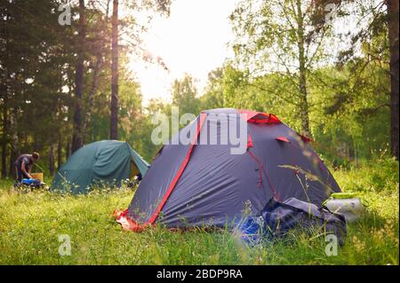 Tourist tents at sunset on the background of the forest Stock Photo