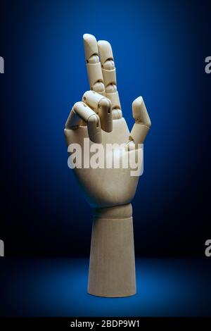 Artificial intelligence wooden hand front view with two fingers pointing up on a classic blue background Stock Photo