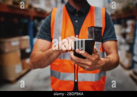 Closeup of man hands using mobile phone while in warehouse in uniform Stock Photo