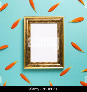 Empty photo frame with orange gerbera daisy flower petals on blue background. Floral composition, flat lay, top view, copy space Stock Photo
