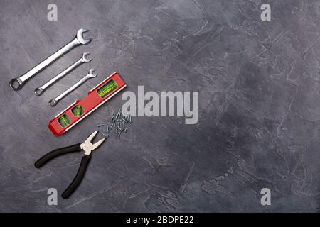 Different hand tools for construction, repair- pliers, level tool, spanner on grey background. Top view, flay lay. Free space. Copy space.  Stock Photo