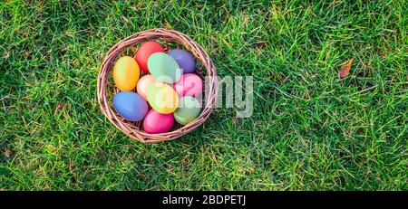 Overhead view of colorful easter eggs in basket on the grass. Stock Photo