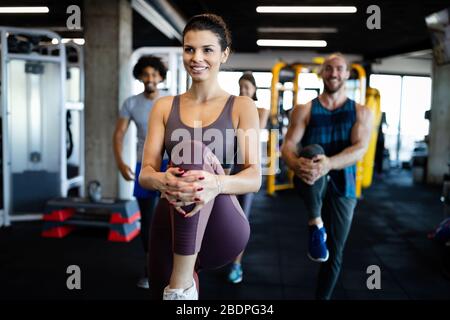 Group of sportive people in gym. Happy fit friends workout