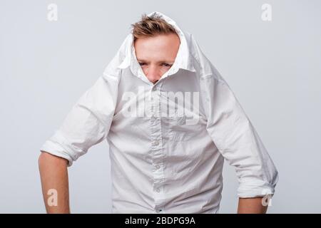 Shy caucasian man hiding behind his white shirt. Concept of being shy or trying to keep distance. Stock Photo