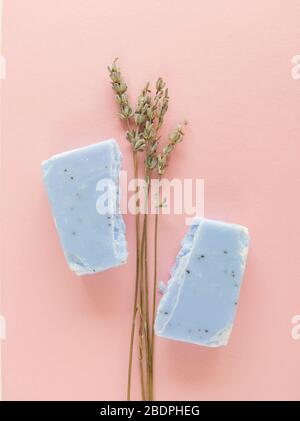 Homemade lavender soap bar and lavender flowers on pastel pink background. Stock Photo
