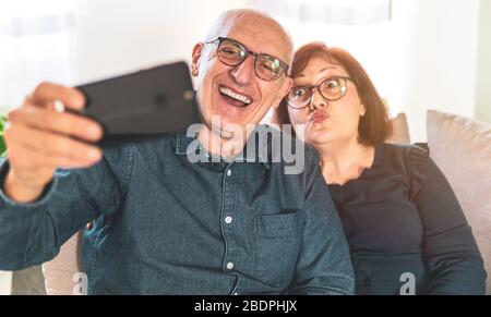 Portrait of joyful senior married couple - Retired couple enjoying free time taking funny selfie - middle-aged couple having fun together using smartp Stock Photo