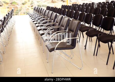 Uniqueness concept. Rows of black folding chairs empty in a conference room . Unique throne or ceremonial armchair with seat and golden details among Stock Photo