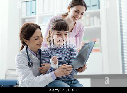 Friendly doctor holding a girl on her lap and showing her an x-ray image of her arm Stock Photo