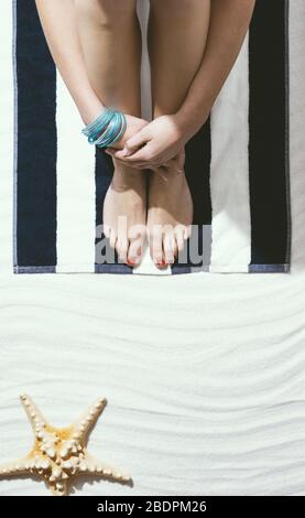 Woman enjoying her summer vacations at the seaside: she is relaxing on the beach and sun tanning Stock Photo