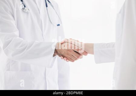 Doctors in lab coats greeting each other with handshake Stock Photo
