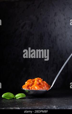 Italian bolognese sauce in spoon on a dark slate Stock Photo
