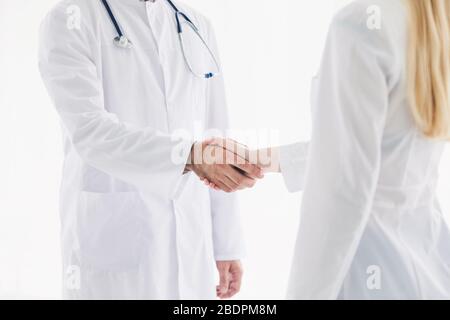 Doctors in lab coats greeting each other with handshake Stock Photo