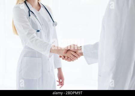 Doctors in lab coats greeting each other with handshake Stock Photo