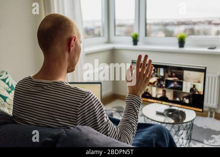 Man working from home. Having a video call meeting with his team on big monitor Stock Photo