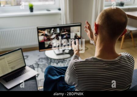 Man working from home. Having a video call meeting with his team on big monitor Stock Photo