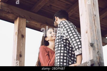 Romantic loving couple staring at each other in a wooden gazebo, feelings and relationships concept Stock Photo